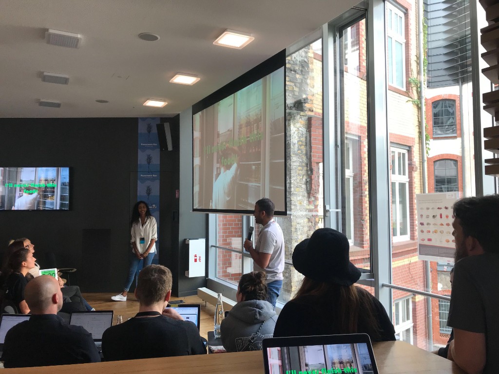 Sahra Malin presenting on stage at a tech event